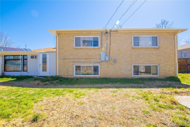 rear view of house featuring a yard, brick siding, and fence