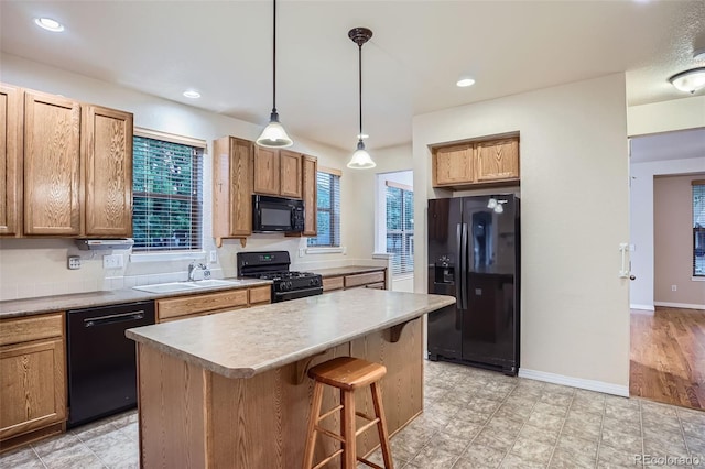 10193 E 29th Ave, Denver, CO 80238 - kitchen featuring black appliances, a breakfast bar area, a kitchen island, decorative light fixtures, and light countertops