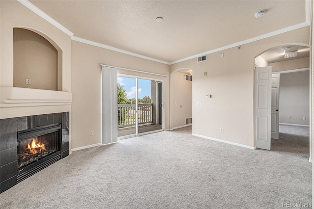 unfurnished living room with a tile fireplace, carpet flooring, and ornamental molding