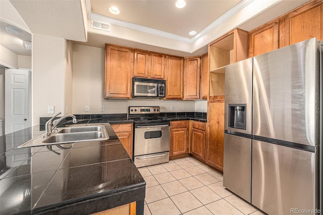 kitchen featuring sink, crown molding, appliances with stainless steel finishes, a tray ceiling, and light tile patterned flooring