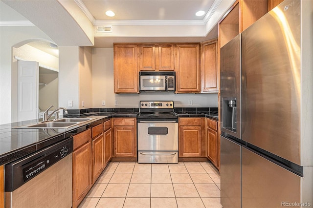 kitchen with ornamental molding, sink, appliances with stainless steel finishes, and a tray ceiling