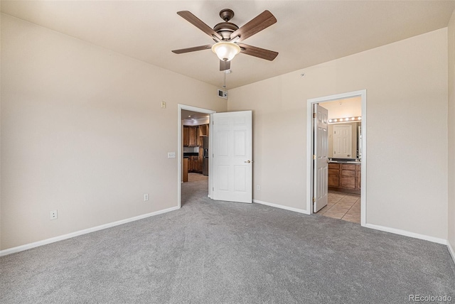 unfurnished bedroom featuring ceiling fan, light colored carpet, and ensuite bath