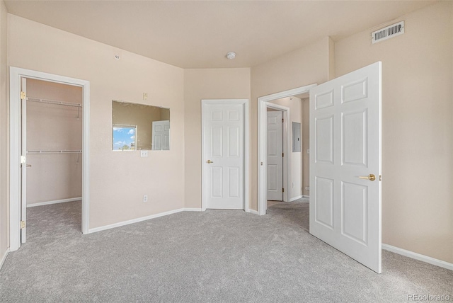 unfurnished bedroom featuring light colored carpet, a walk in closet, and a closet