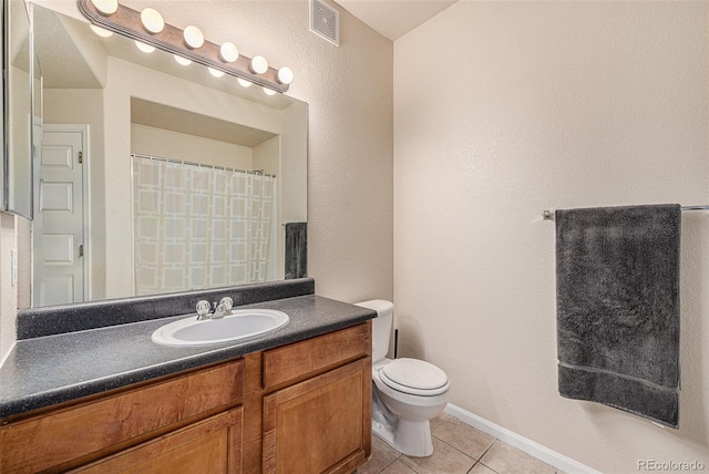 bathroom with toilet, vanity, and tile patterned floors