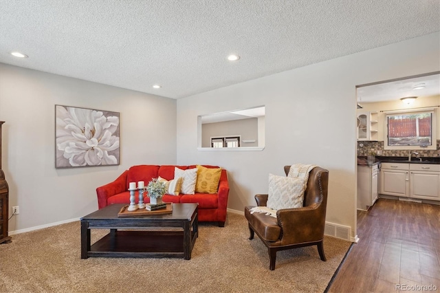 living area with a textured ceiling, recessed lighting, wood finished floors, visible vents, and baseboards