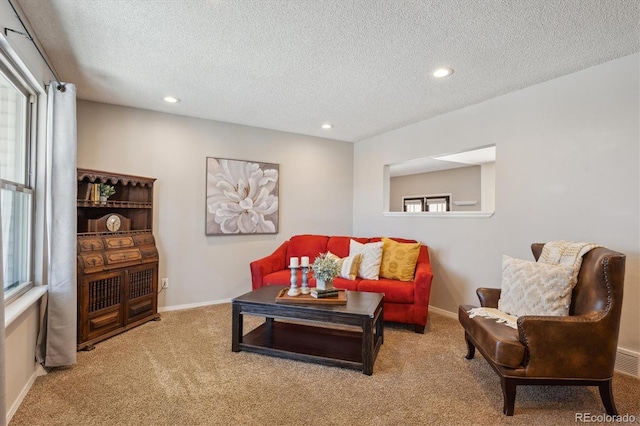 living area with carpet flooring, a textured ceiling, and baseboards