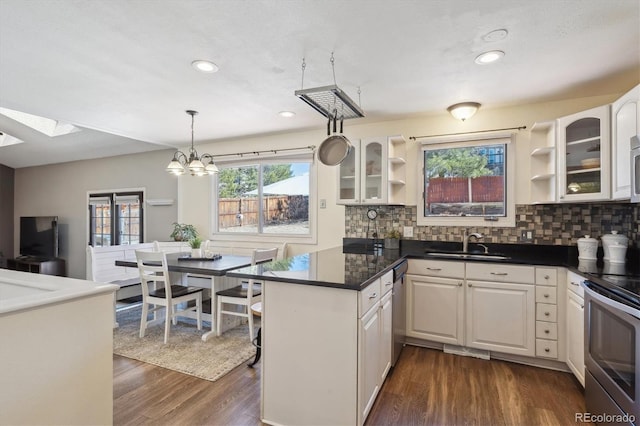 kitchen featuring a peninsula, dark wood-style flooring, a sink, appliances with stainless steel finishes, and open shelves