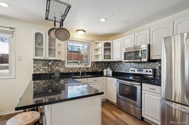 kitchen with open shelves, dark countertops, appliances with stainless steel finishes, white cabinetry, and a peninsula