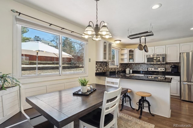 kitchen with stainless steel appliances, white cabinets, tasteful backsplash, dark countertops, and glass insert cabinets