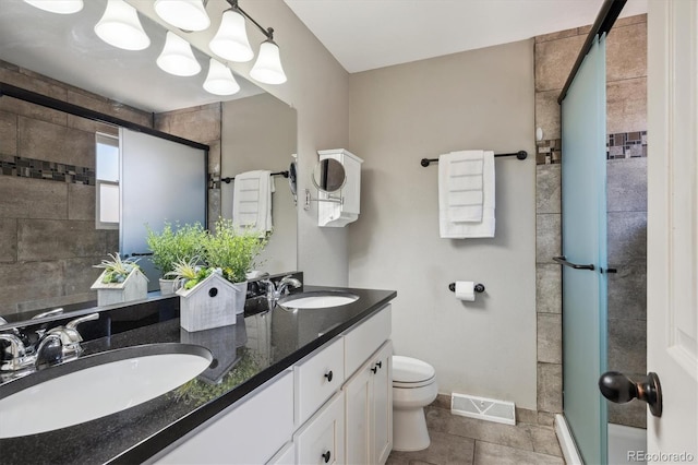 bathroom with toilet, double vanity, a sink, and visible vents