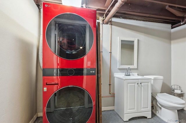 laundry area featuring stacked washer and dryer, baseboards, laundry area, and a sink