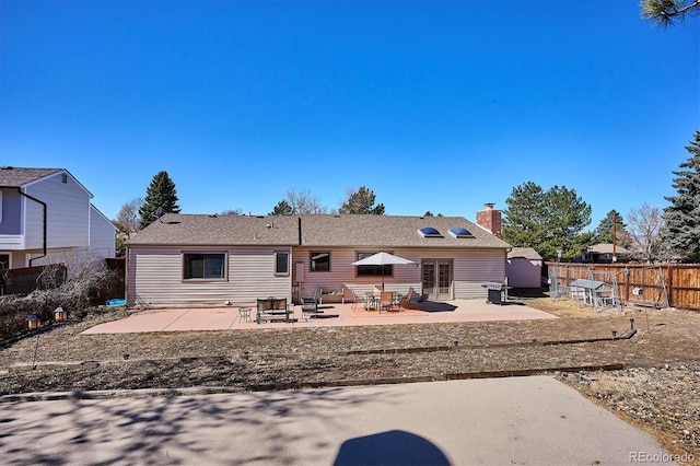 rear view of house with a patio, a chimney, and fence