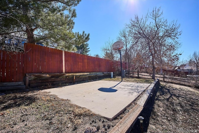 exterior space with basketball hoop and fence