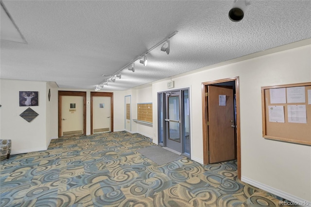 unfurnished room featuring carpet flooring, a textured ceiling, and rail lighting