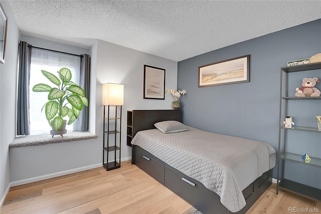 bedroom featuring light wood-type flooring and a textured ceiling