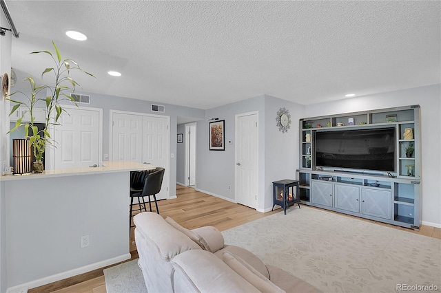 living room with light wood-type flooring and a textured ceiling