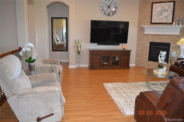 7851 E 148th Dr, Thornton, CO 80602 - living area with a glass covered fireplace, baseboards, arched walkways, and wood finished floors