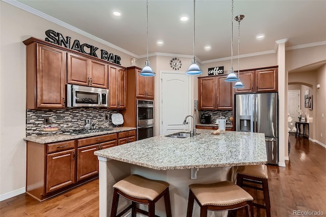 7851 E 148th Dr, Thornton, CO 80602 - kitchen with a breakfast bar area, arched walkways, tasteful backsplash, a sink, and stainless steel appliances