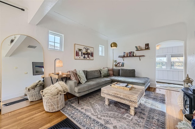 living area featuring plenty of natural light, arched walkways, and hardwood / wood-style flooring