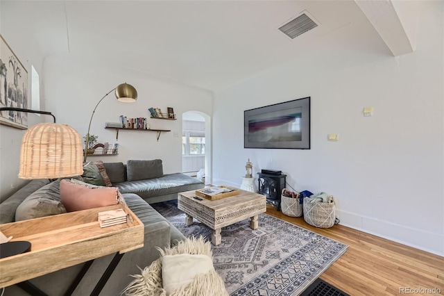 living area featuring visible vents, arched walkways, baseboards, and wood finished floors
