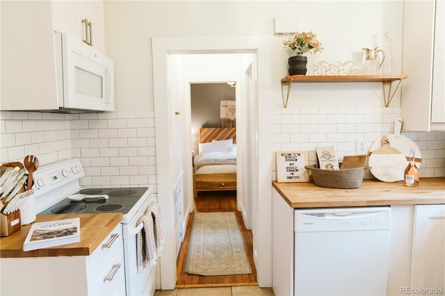 kitchen with white appliances, backsplash, white cabinets, and wooden counters