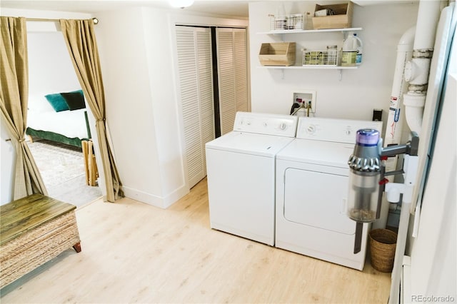 clothes washing area featuring baseboards, laundry area, light wood-type flooring, and washer and dryer