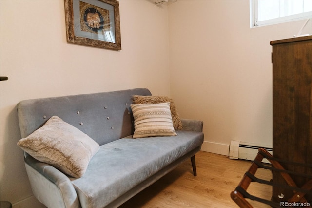 sitting room with baseboards, wood finished floors, and a baseboard radiator