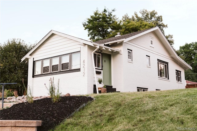exterior space with brick siding and a front yard