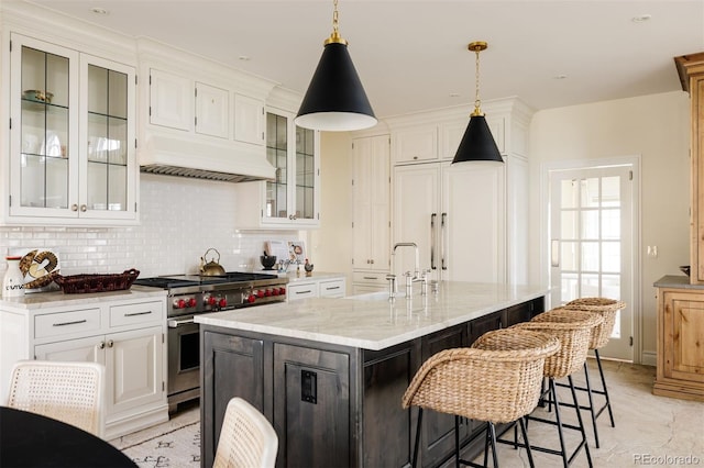 5700 S Steele St, Greenwood Village, CO 80121 - kitchen with range with two ovens, tasteful backsplash, white cabinets, light stone counters, and a kitchen island with sink