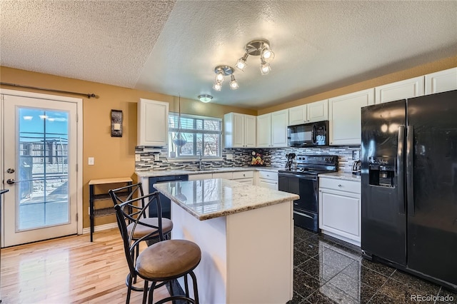 kitchen featuring a center island, backsplash, white cabinets, black appliances, and a kitchen breakfast bar