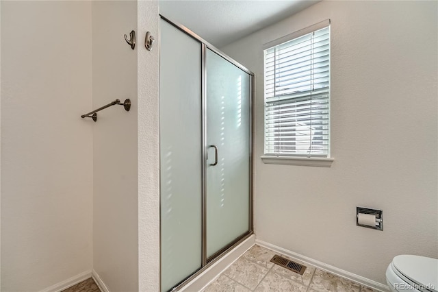 full bath with toilet, a stall shower, visible vents, and baseboards