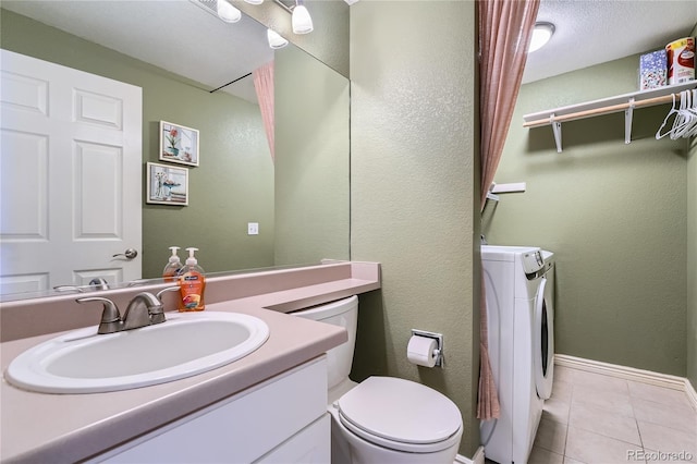 bathroom with a textured wall, toilet, vanity, tile patterned floors, and washer / clothes dryer