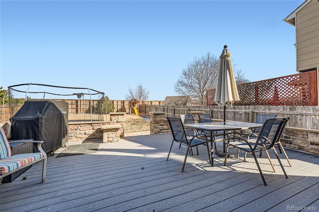 wooden deck featuring outdoor dining area, a fenced backyard, and grilling area