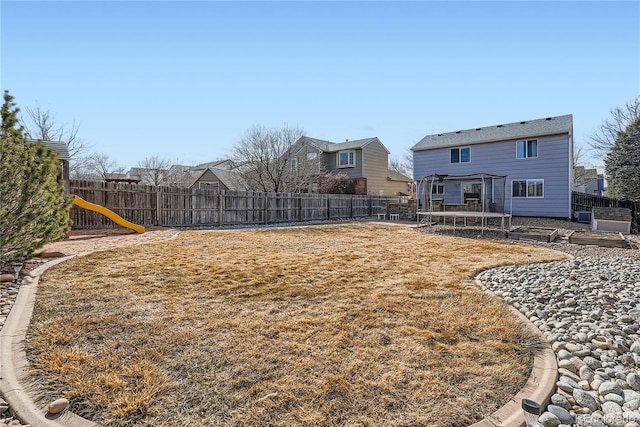 view of yard featuring a fenced backyard, a trampoline, and a playground