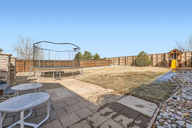 view of yard with a trampoline, a fenced backyard, and a patio