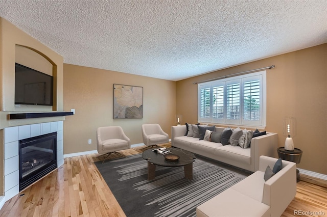 5130 S Wenatchee St, Aurora, CO 80015 - living area featuring wood finished floors, a textured ceiling, a tile fireplace, and baseboards