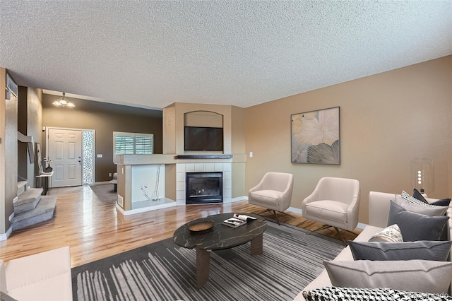 5130 S Wenatchee St, Aurora, CO 80015 - living room featuring light wood-type flooring, baseboards, a textured ceiling, and a fireplace