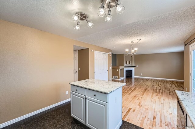 5130 S Wenatchee St, Aurora, CO 80015 - kitchen featuring a chandelier, baseboards, a textured ceiling, gray cabinets, and a kitchen island