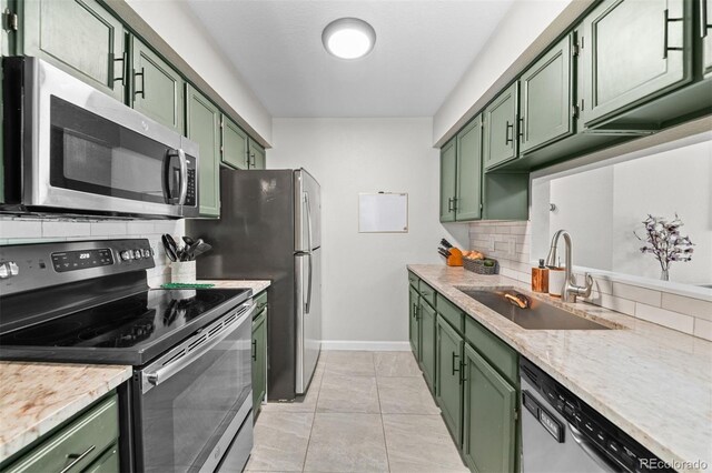 3600 S Pierce St Unit 7-208, Denver, CO 80235 - kitchen with green cabinetry, stainless steel appliances, tasteful backsplash, and light stone countertops