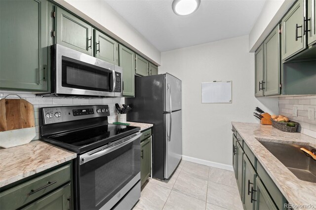 3600 S Pierce St Unit 7-208, Denver, CO 80235 - kitchen featuring green cabinets, stainless steel appliances, backsplash, and light countertops