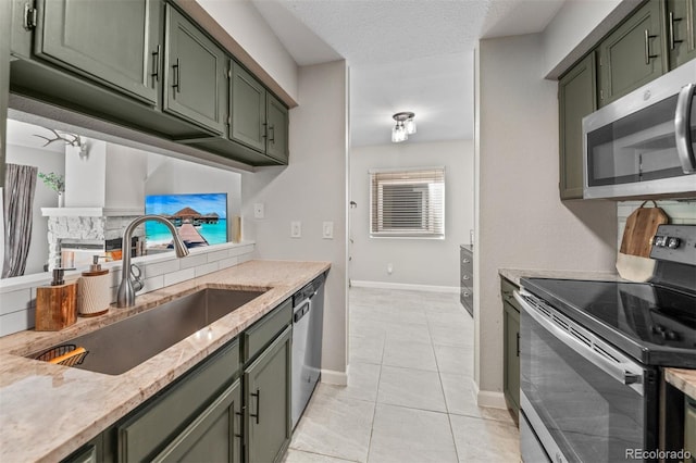 3600 S Pierce St Unit 7-208, Denver, CO 80235 - kitchen featuring appliances with stainless steel finishes, green cabinets, light tile patterned floors, light stone countertops, and a textured ceiling