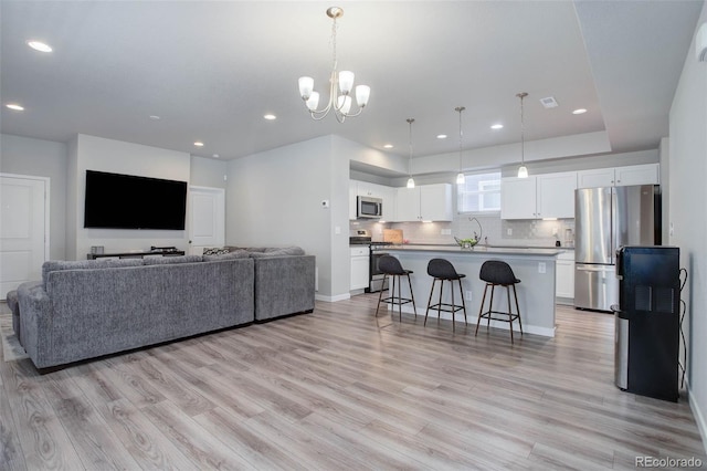 living room with light wood-type flooring, a chandelier, and sink