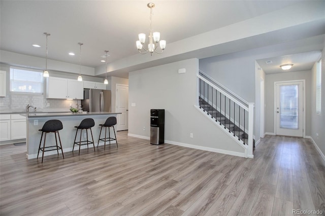 kitchen featuring white cabinetry, hanging light fixtures, stainless steel refrigerator, and a kitchen island