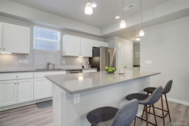 kitchen featuring white cabinetry, appliances with stainless steel finishes, and hanging light fixtures