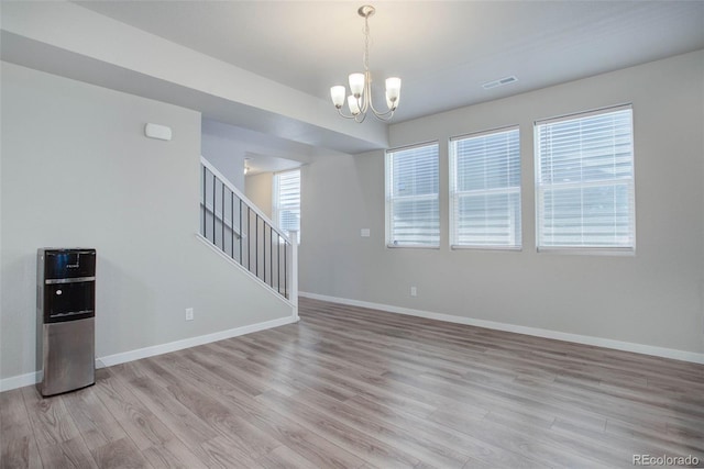 unfurnished living room with a notable chandelier and light hardwood / wood-style flooring