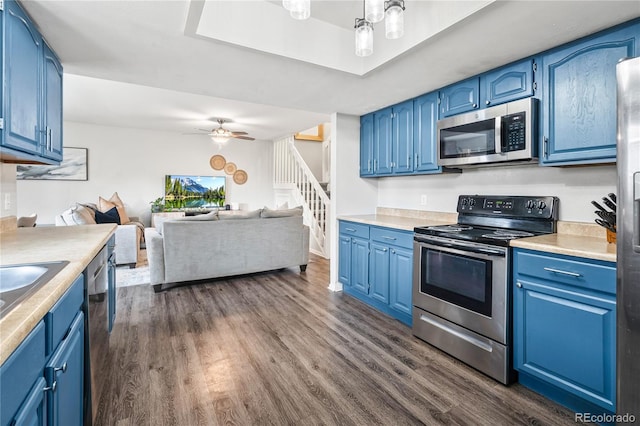 1080 S Yampa St, Aurora, CO 80017 - kitchen featuring appliances with stainless steel finishes, blue cabinetry, dark wood-style flooring, open floor plan, and light countertops