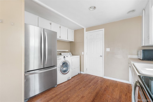 6150 E 65th Ave, Commerce City, CO 80022 - kitchen with separate washer and dryer, stainless steel appliances, white cabinets, light wood-type flooring, and light countertops