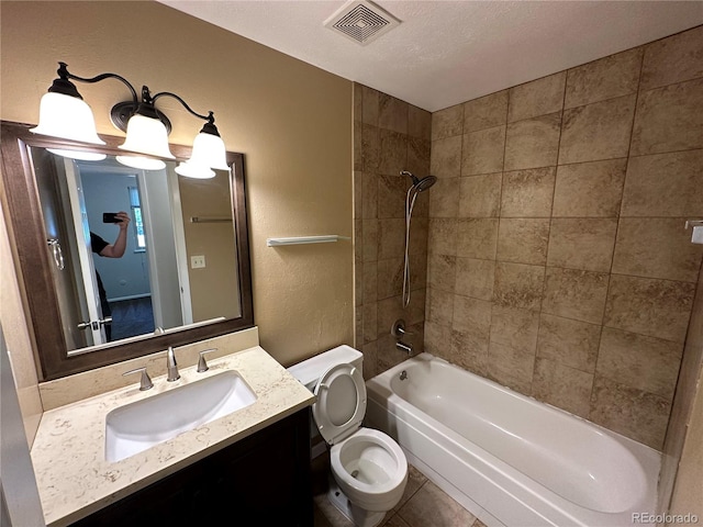 full bathroom featuring toilet, large vanity, tiled shower / bath combo, a textured ceiling, and tile floors