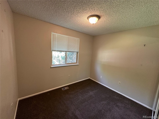 empty room with a textured ceiling and dark carpet