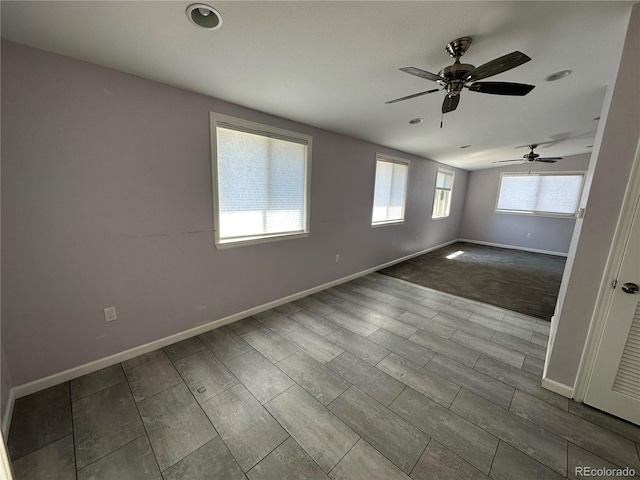 empty room with ceiling fan, a wealth of natural light, and light wood-type flooring